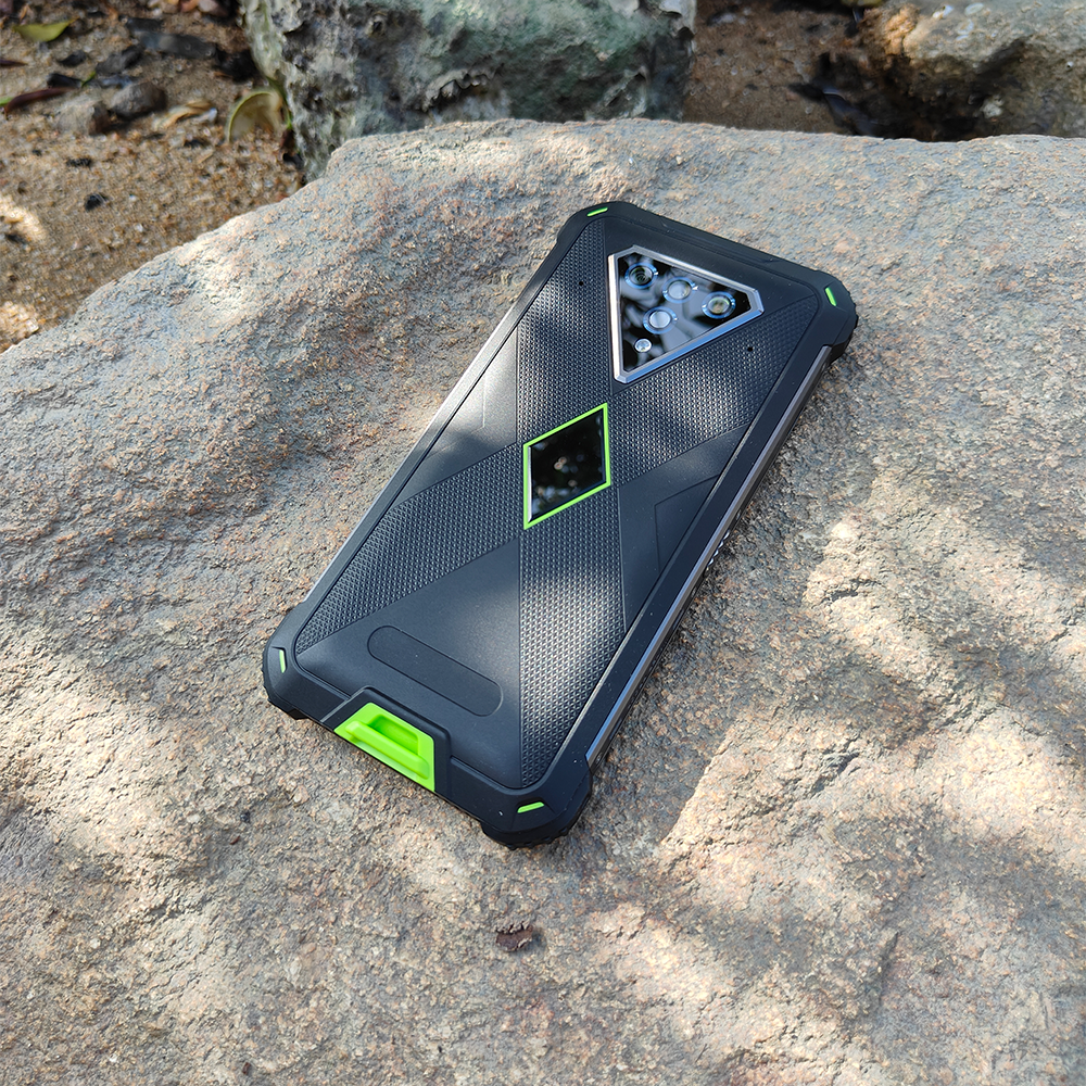 Black and green Phonemax rugged smartphone charging on a rock outdoors
