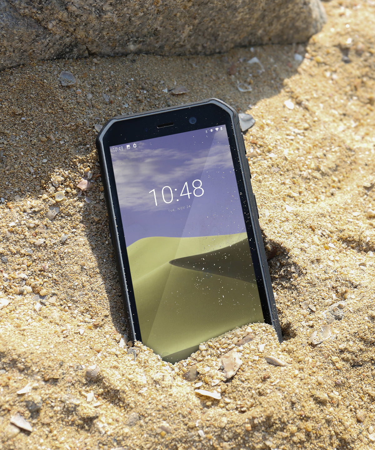 Black Phonemax Q9 Mini compact smartphone standing on wet sand