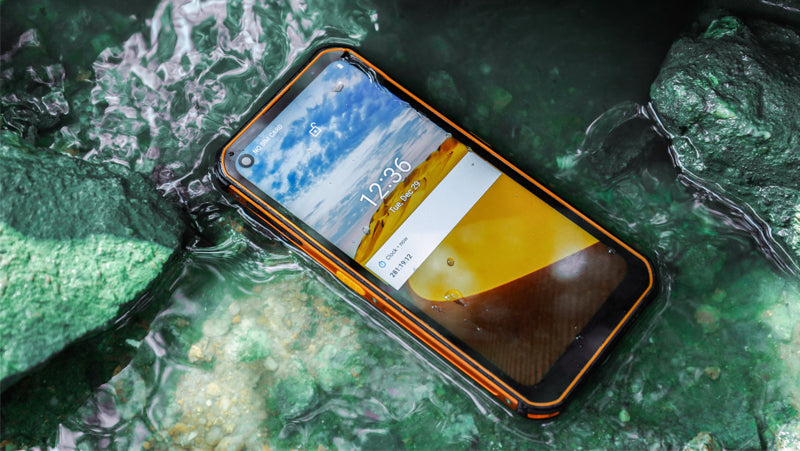 Orange Phonemax rugged smartphone lying in shallow water on a rocky surface