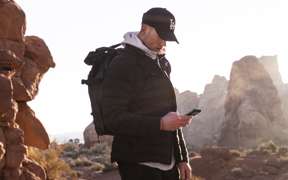 Outdoor hiker checking a smartphone while standing among rocky desert terrain