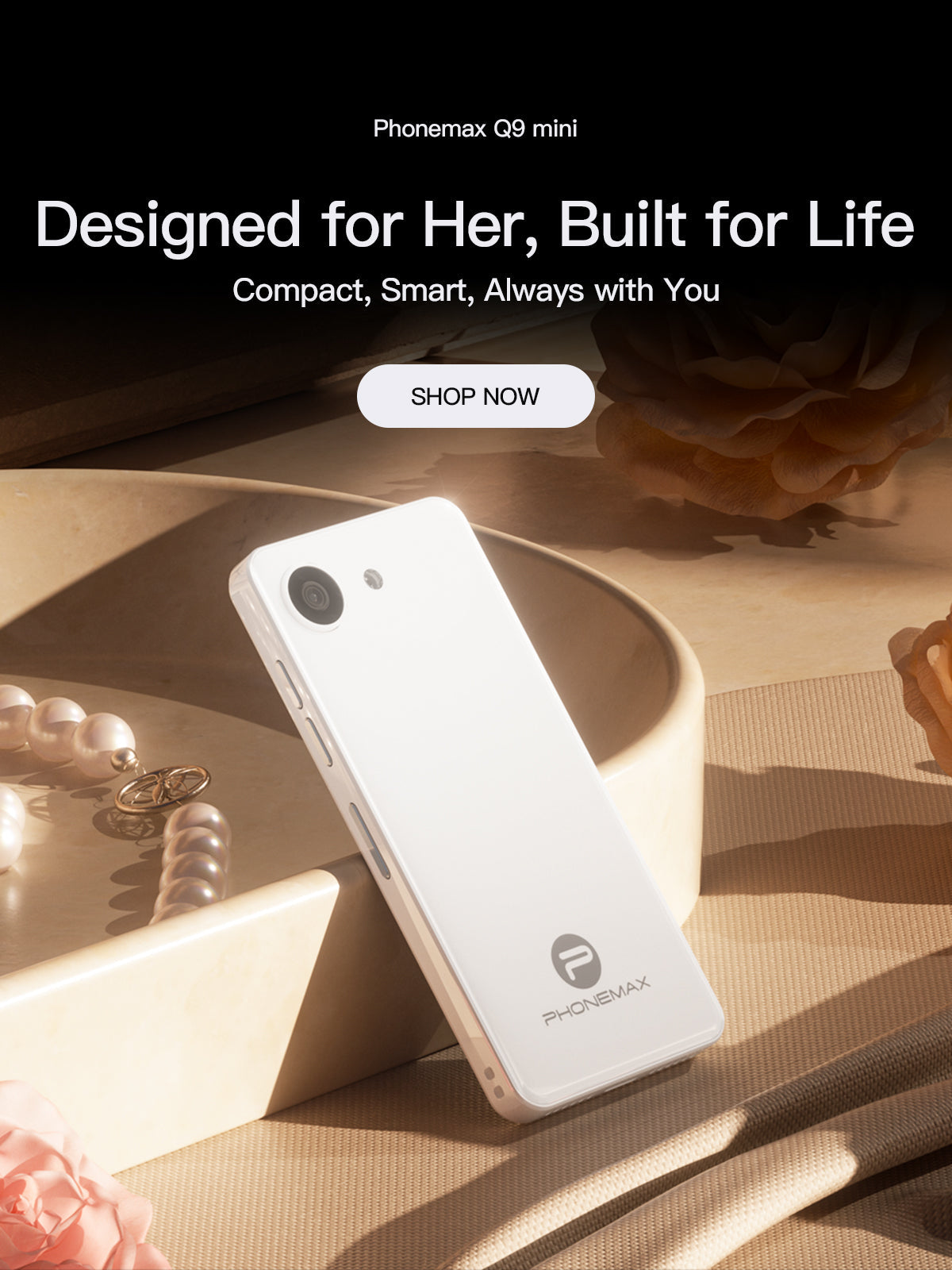 White Phonemax Q9 Mini compact phone displayed beside jewelry on a warm studio set