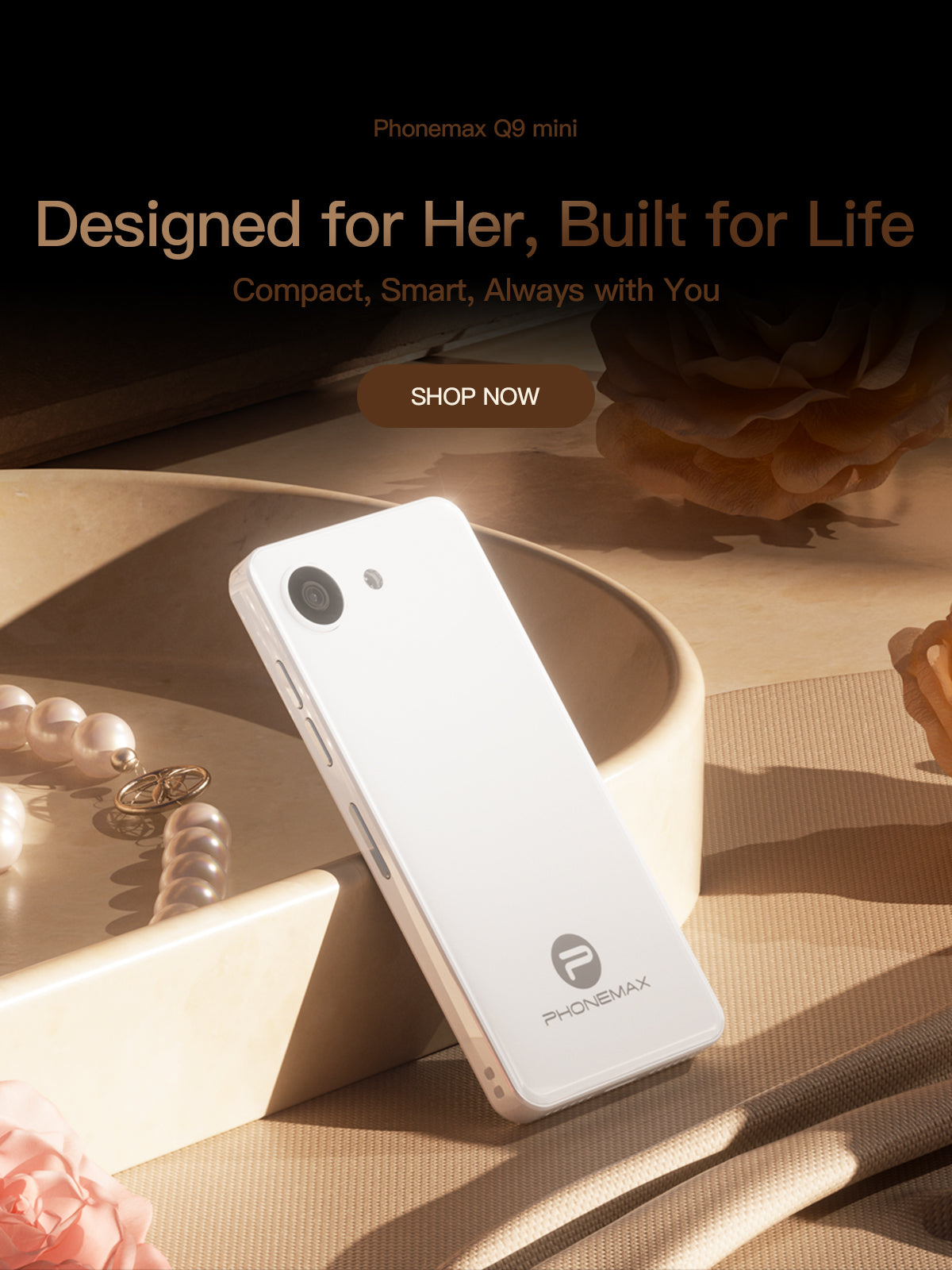 White Phonemax Q9 Mini compact phone displayed beside jewelry on a warm studio set