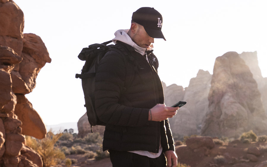 Outdoor hiker checking a smartphone while standing among rocky desert terrain